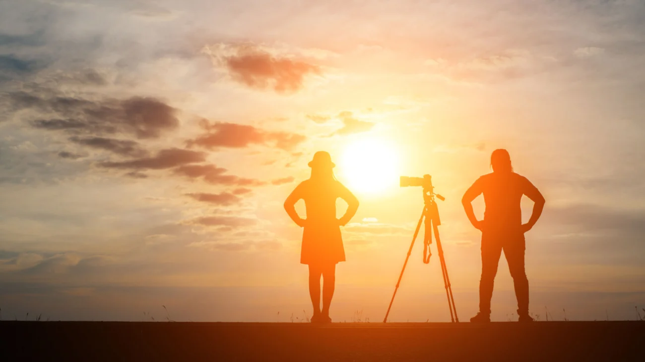 Silhouette of a photographer shoots a photo of his girl at sunse